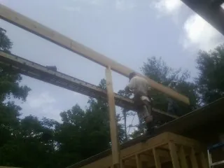 Carpenter setting a ridge beam over a new addition frame — Ice Dam Removal by Roofing Brothers in Moretown