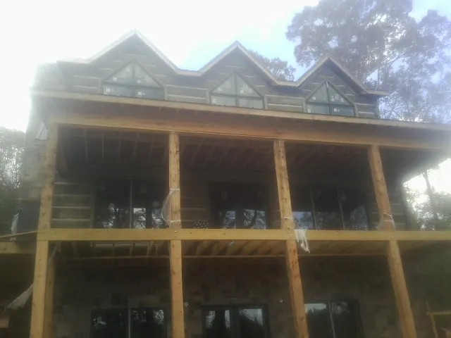Dormers and porch framing on a large log home under construction — Roof Coating work by our crew in Moretown