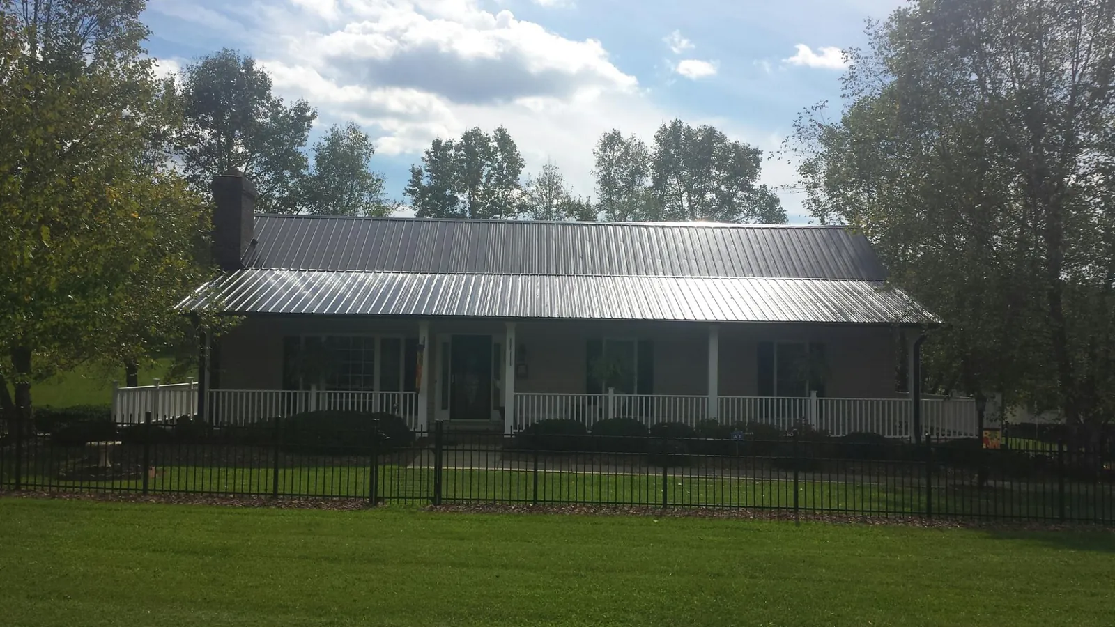 Gray metal roof on a brick ranch with a full width front porch — Gutter Guard Installation work by our crew in Moretown