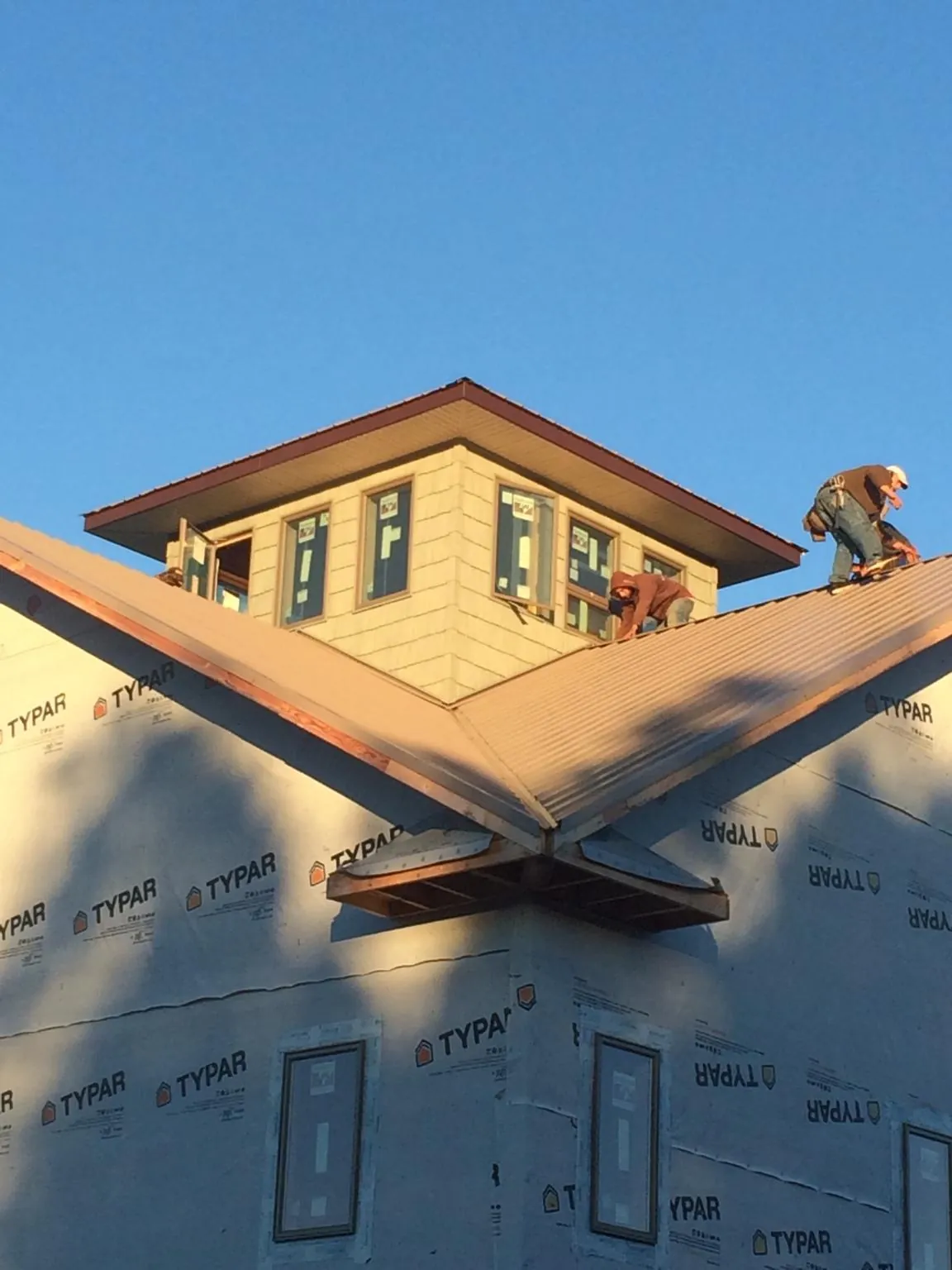 Roofers working around a rooftop cupola on a new metal roof at sunset — Roof Waterproofing in Moretown by Roofing Brothers
